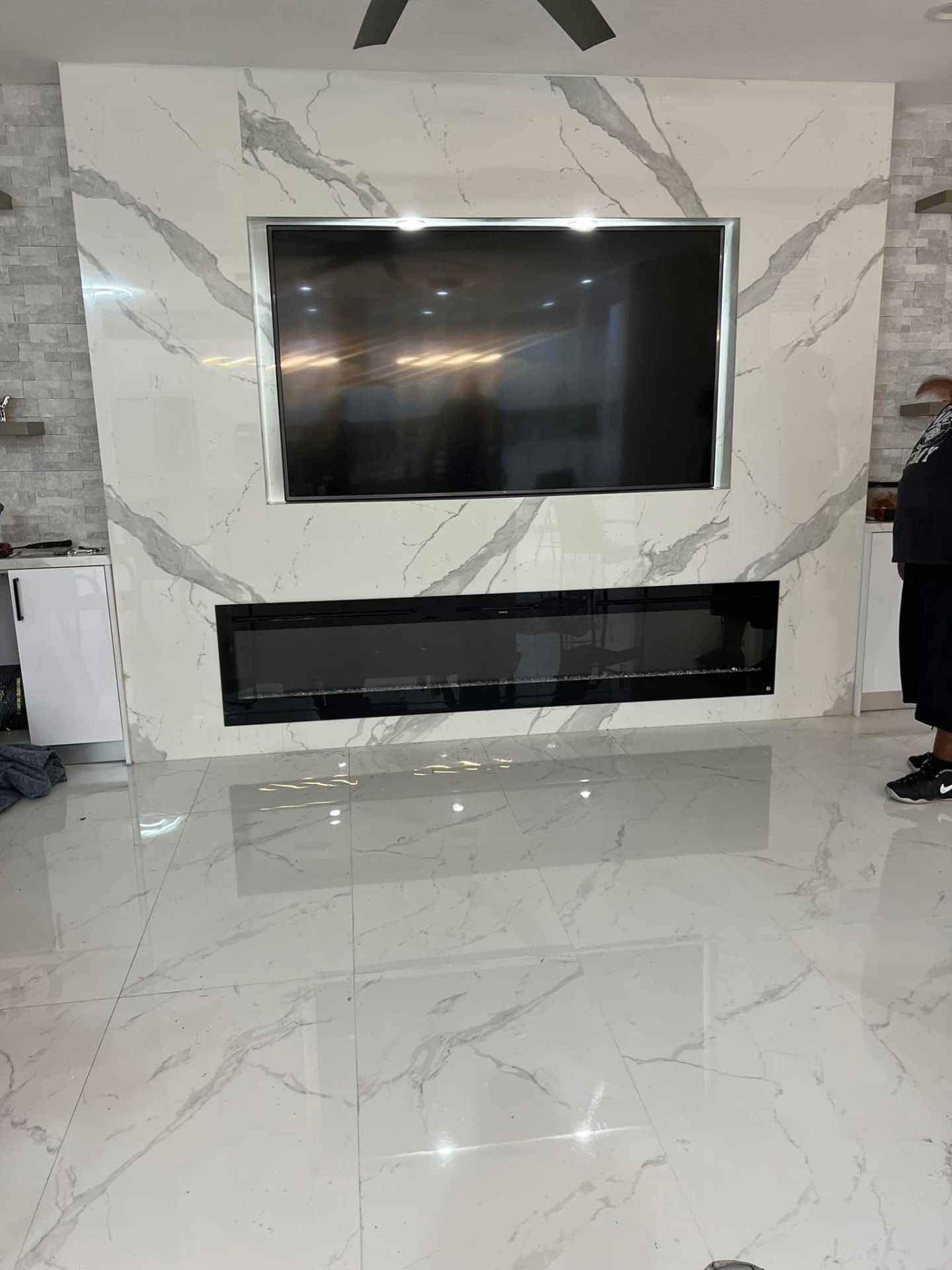 Full-height marble feature wall with recessed TV and linear electric fireplace