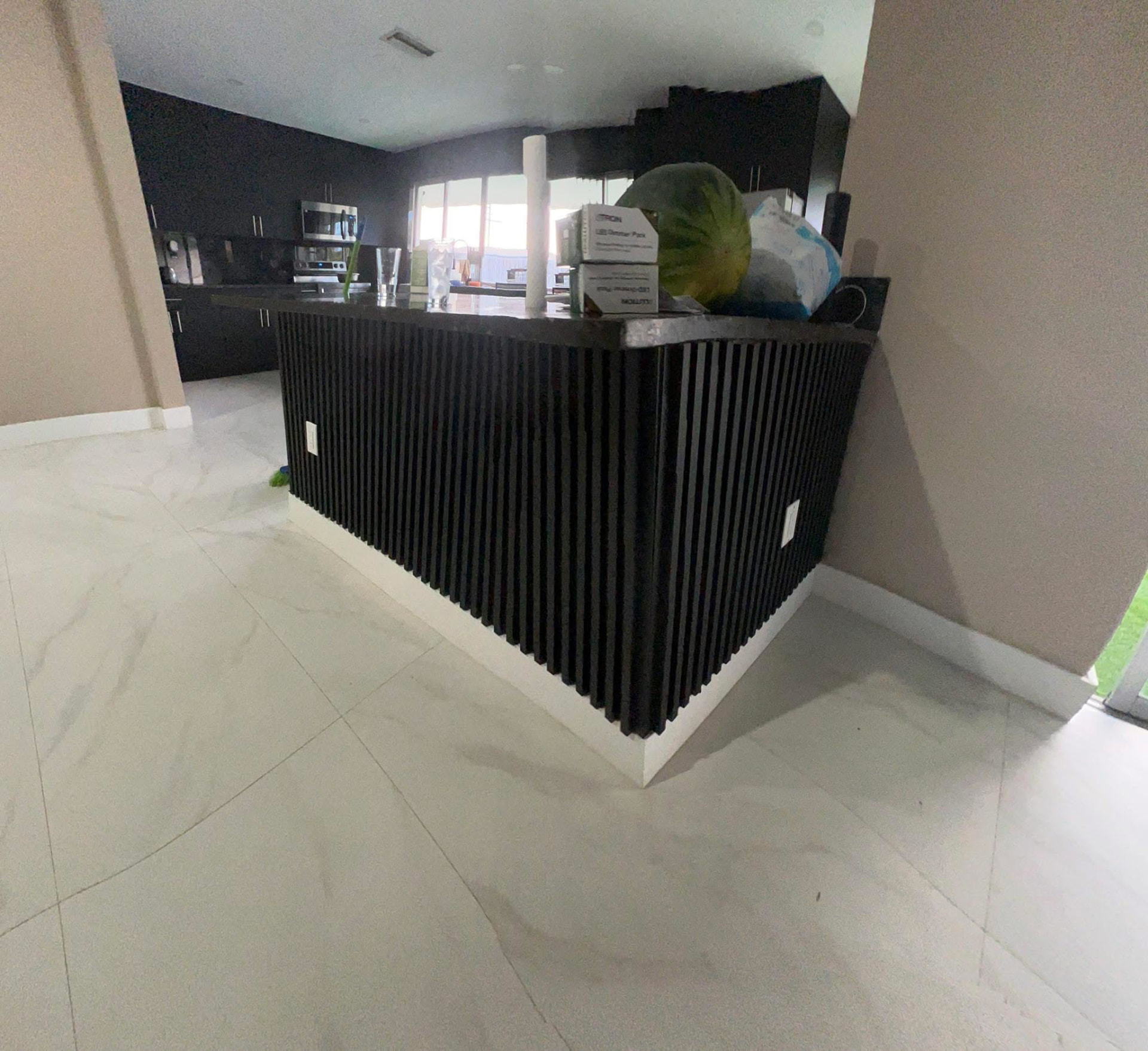Black slatted kitchen island with stone countertop and porcelain tile flooring